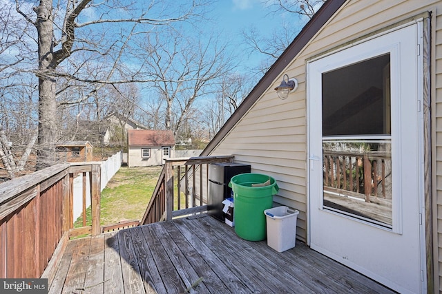 wooden terrace with an outbuilding, a lawn, and fence