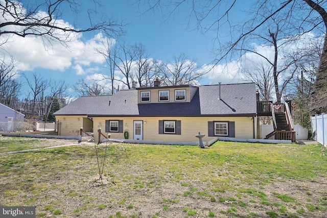 rear view of property featuring fence, a yard, stairway, roof with shingles, and a chimney