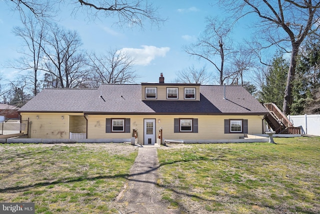 view of front of home featuring a chimney, a shingled roof, a front yard, and fence