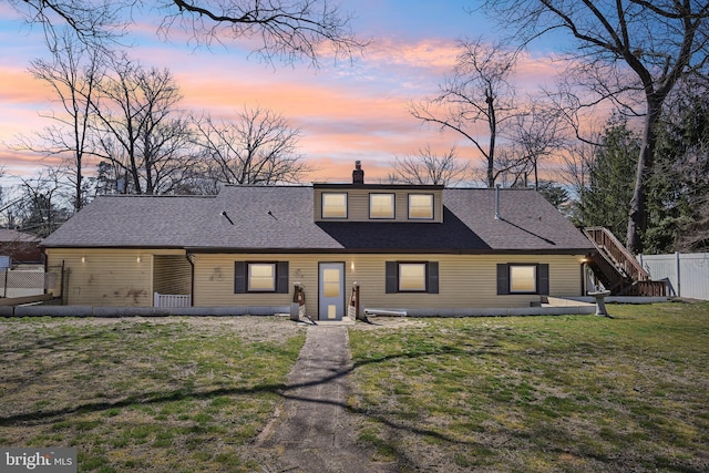 view of front of property featuring a shingled roof, a lawn, a chimney, and fence