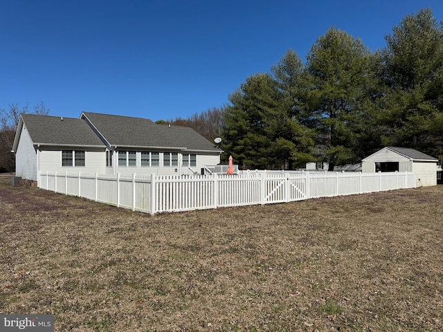 view of side of property featuring a gate, roof with shingles, a yard, and fence