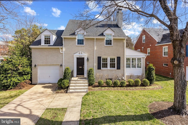 traditional home featuring driveway, an attached garage, a front yard, brick siding, and a chimney