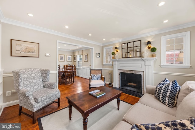 living room with recessed lighting, a brick fireplace, crown molding, and wood finished floors