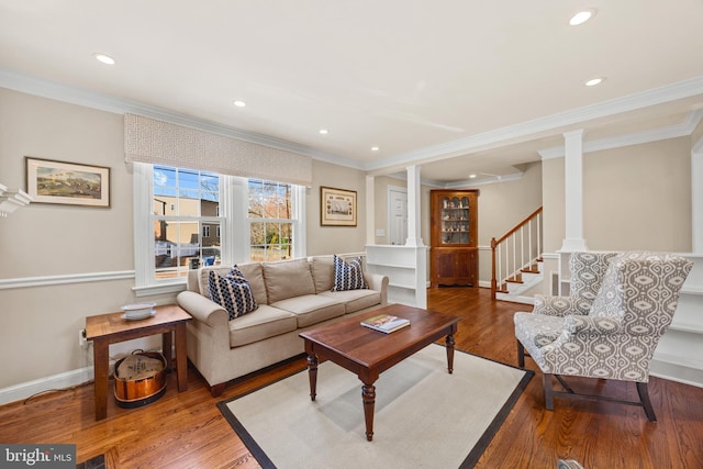 living room with stairway, wood finished floors, baseboards, ornate columns, and ornamental molding