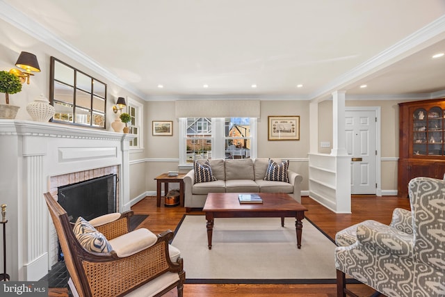 living area with a fireplace, decorative columns, wood finished floors, and ornamental molding