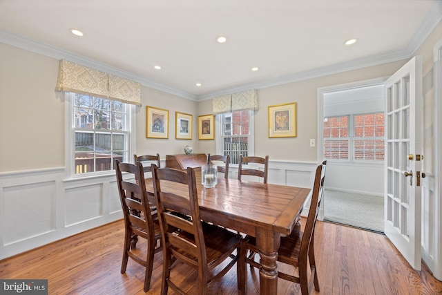 dining area featuring wainscoting, crown molding, and light wood-type flooring