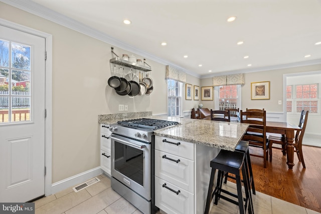 kitchen with crown molding, high end range, visible vents, and white cabinets