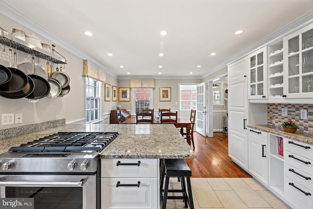 kitchen featuring stainless steel range, white cabinets, crown molding, and tasteful backsplash