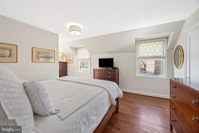 bedroom with baseboards, lofted ceiling, and wood finished floors