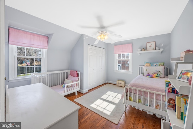 bedroom featuring baseboards, ceiling fan, lofted ceiling, wood finished floors, and a closet