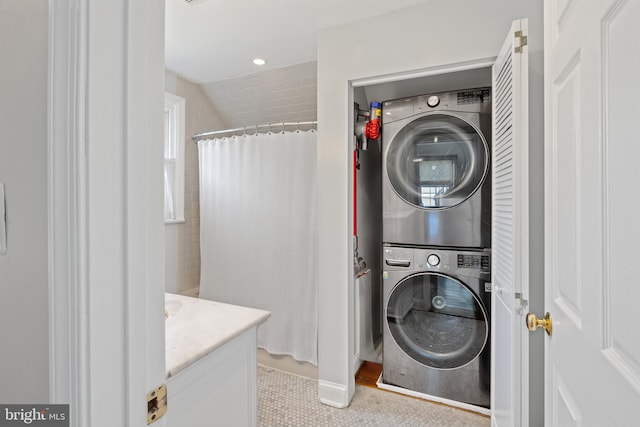 clothes washing area featuring recessed lighting, laundry area, and stacked washing maching and dryer