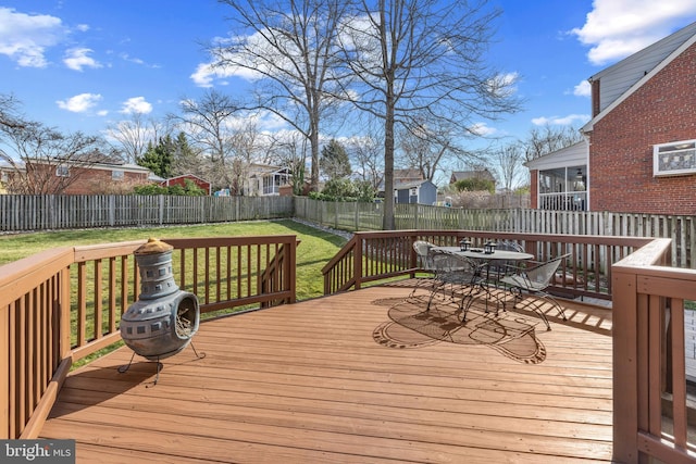 deck featuring outdoor dining area, a fenced backyard, and a lawn