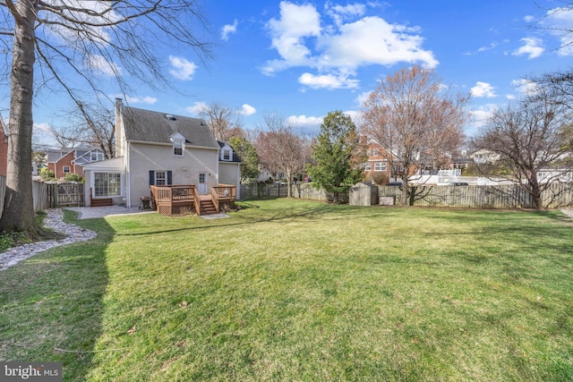 view of yard featuring a deck, an outdoor structure, and a fenced backyard