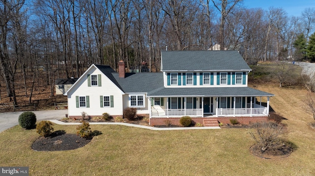 colonial inspired home featuring covered porch, a chimney, a front lawn, and roof with shingles