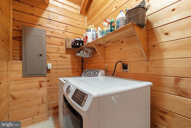 clothes washing area with laundry area, wooden walls, electric panel, and washing machine and clothes dryer