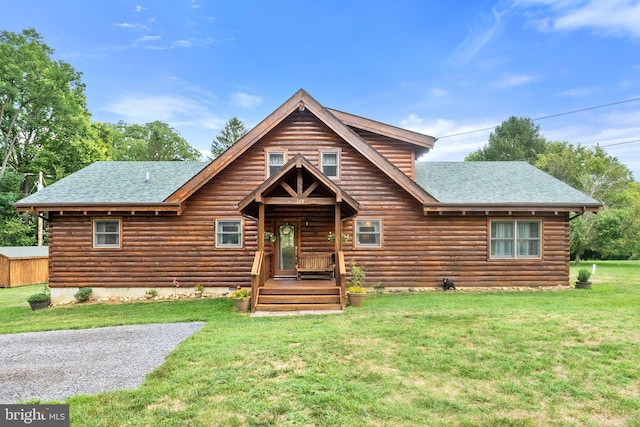 log cabin with log exterior, a shingled roof, and a front lawn