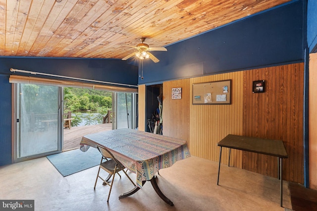 dining room featuring lofted ceiling, wood walls, wooden ceiling, and ceiling fan