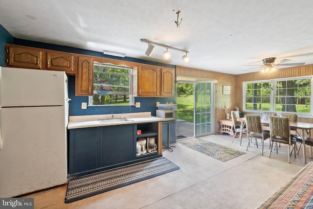 kitchen with concrete floors, light countertops, white appliances, a textured ceiling, and a sink