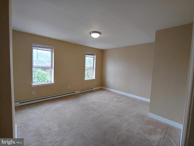 spare room with a baseboard heating unit, carpet, and baseboards