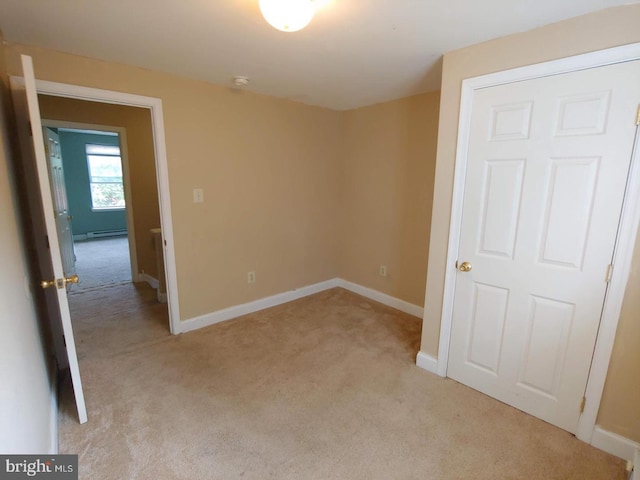 unfurnished bedroom featuring a baseboard radiator, baseboards, and light colored carpet