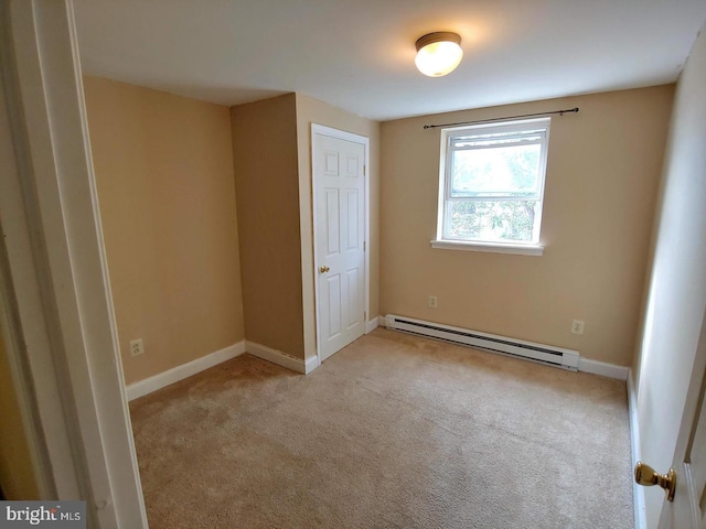 unfurnished bedroom featuring baseboard heating, baseboards, and carpet floors