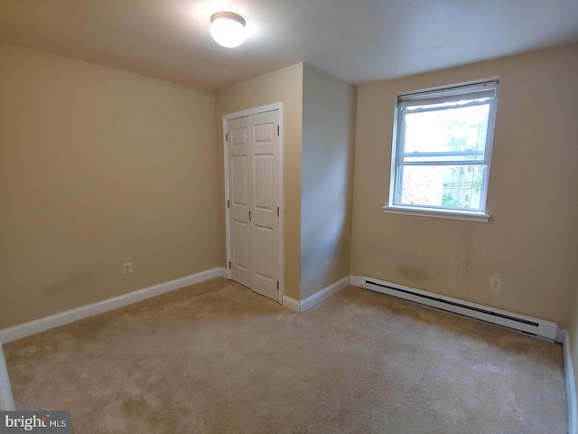 unfurnished bedroom featuring baseboard heating, baseboards, and carpet floors