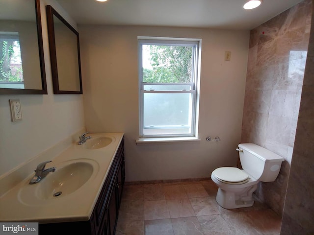 bathroom featuring a sink, baseboards, toilet, and double vanity