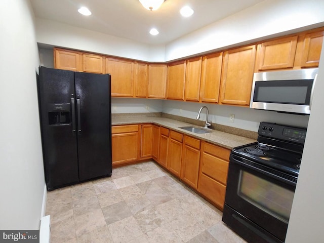 kitchen with a sink, black appliances, recessed lighting, and light countertops