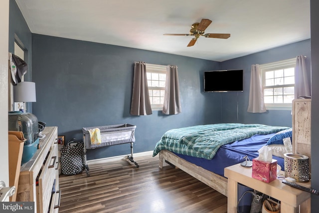 bedroom featuring multiple windows, a ceiling fan, baseboards, and wood finished floors