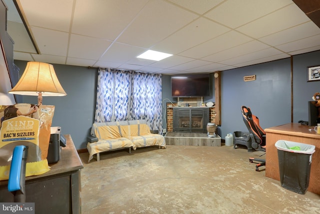 office featuring a drop ceiling, concrete flooring, and a fireplace