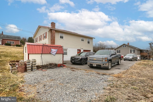 view of home's exterior with a chimney and gravel driveway