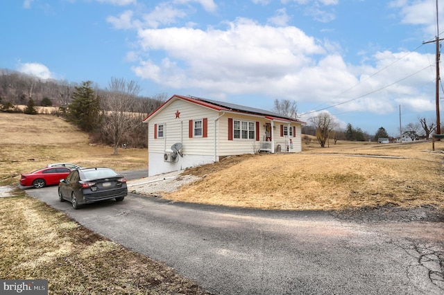 single story home featuring solar panels and driveway