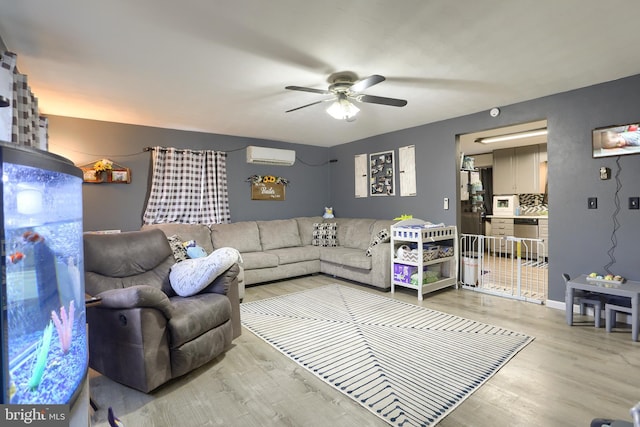 living area featuring a wall mounted air conditioner, light wood-style flooring, baseboards, and ceiling fan