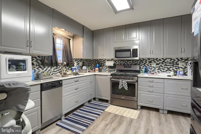 kitchen with a sink, stainless steel appliances, gray cabinets, and light countertops