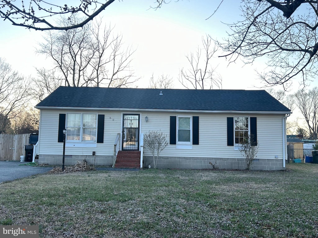 view of front of property with roof with shingles, a front yard, and fence