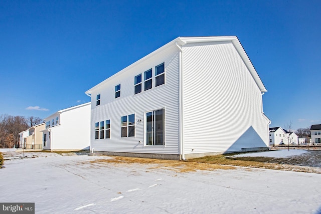 snow covered rear of property with a residential view