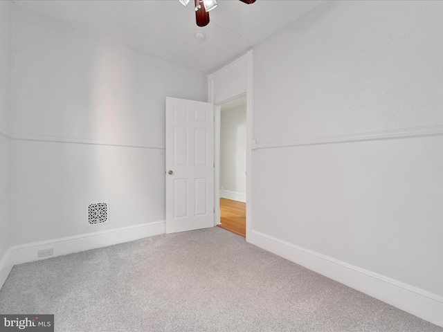 empty room featuring visible vents, carpet floors, baseboards, and a ceiling fan