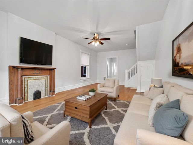 living room featuring stairway, ceiling fan, baseboards, and wood finished floors