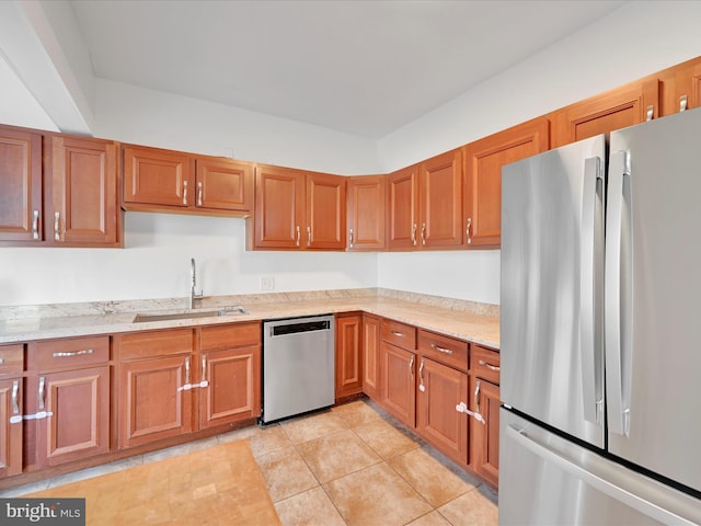 kitchen featuring a sink, stainless steel appliances, brown cabinets, and light tile patterned flooring