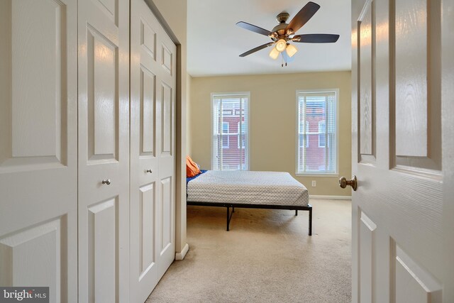 carpeted bedroom with a closet, baseboards, and a ceiling fan