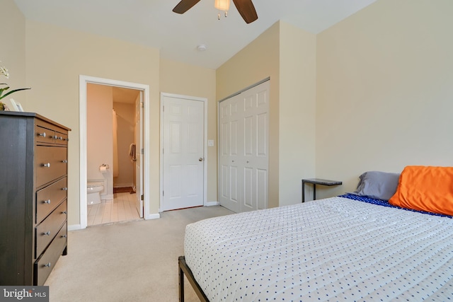 bedroom featuring baseboards, ensuite bath, ceiling fan, a closet, and light carpet