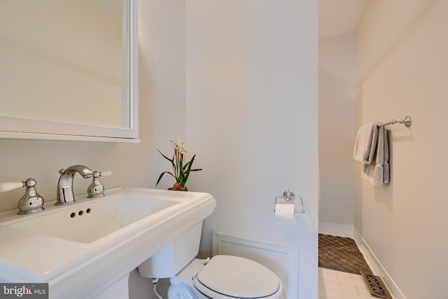 bathroom featuring toilet, baseboards, and a sink