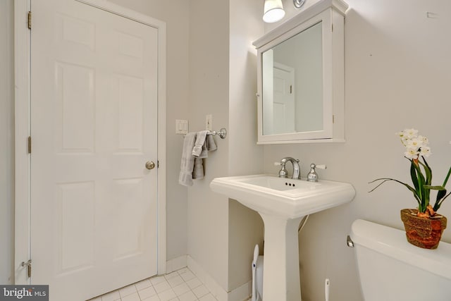 half bathroom with tile patterned floors, toilet, baseboards, and a sink