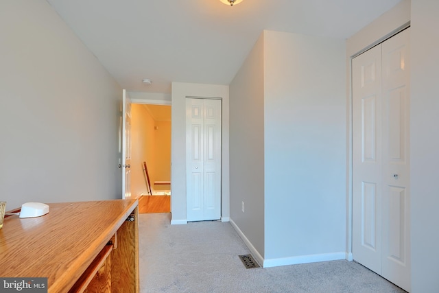 interior space featuring light colored carpet, visible vents, and baseboards