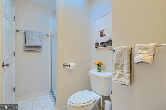 bathroom with a shower stall, toilet, and baseboards