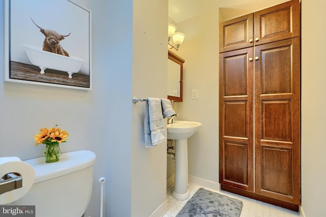 bathroom featuring a sink, baseboards, toilet, and tile patterned flooring