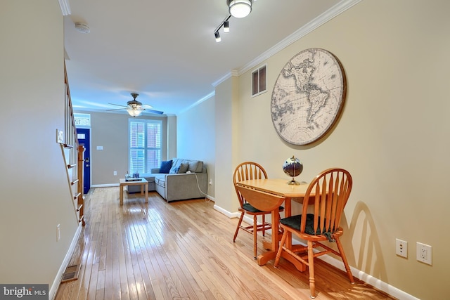 dining area featuring visible vents, baseboards, crown molding, and light wood finished floors