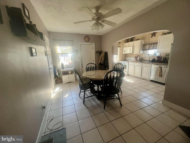 dining area featuring light tile patterned floors, arched walkways, a textured ceiling, and a ceiling fan