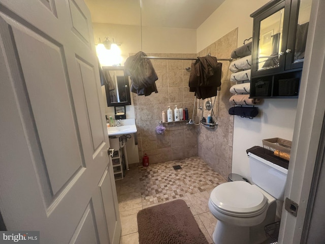 full bath featuring a tile shower, tile patterned floors, toilet, and vanity