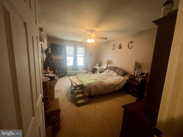 bedroom featuring carpet flooring, radiator, ceiling fan, and a textured ceiling